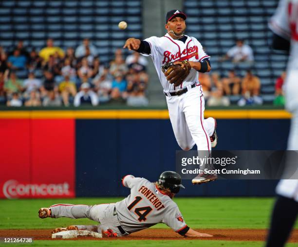 Alex Gonzalez of the Atlanta Braves turns a double play against Mike Fontenot of the San Francisco Giants at Turner Field on August 16, 2011 in...