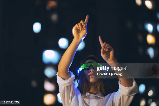 young businesswoman using augmented reality glasses at night - bci stockfoto's en -beelden