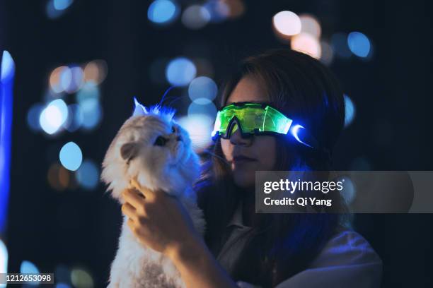 young woman wearing augmented reality glasses hugging a cat - cat vr stock-fotos und bilder