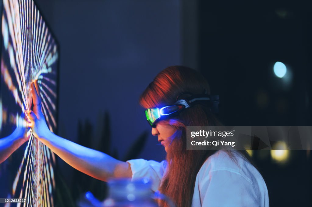 Young woman wearing augmented reality glasses touching screen with hands