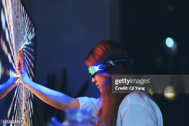 young woman wearing augmented reality glasses touching screen with hands - virtual reality simulator - fotografias e filmes do acervo