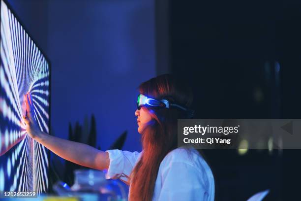 young woman wearing augmented reality glasses touching screen with hands - bokeh computer screen stock pictures, royalty-free photos & images