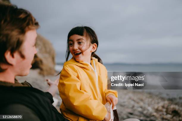 cute little girl having fun at beach in winter, tokyo - regenmantel stock-fotos und bilder