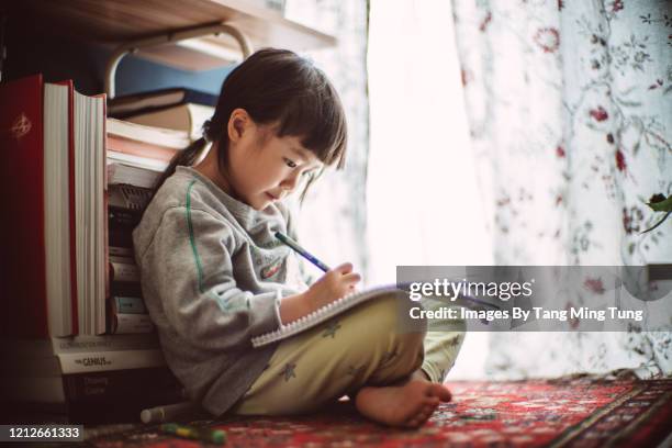 little girl drawing on a sketch book at home - girl sitting on floor stock-fotos und bilder