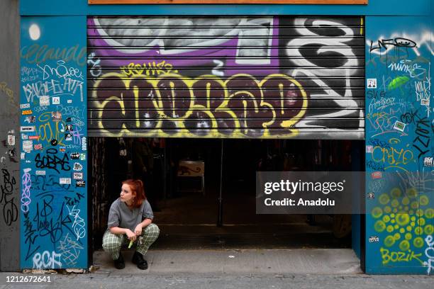 Woman is seen in front of a store pulls up its shutter as a number of businesses reopened 55 days later for the first time after the measures taken...