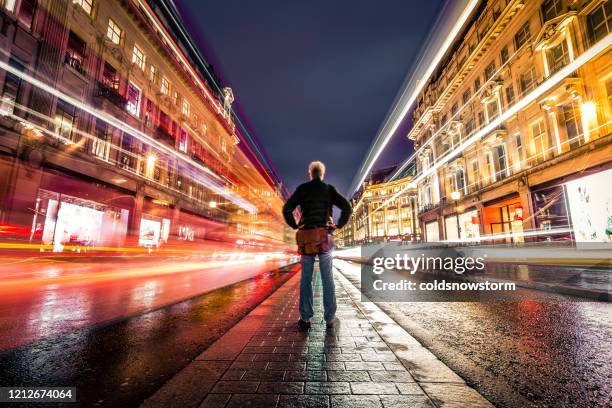 one man on busy city street at night long exposure with blurred motion - lights long exposure stock pictures, royalty-free photos & images