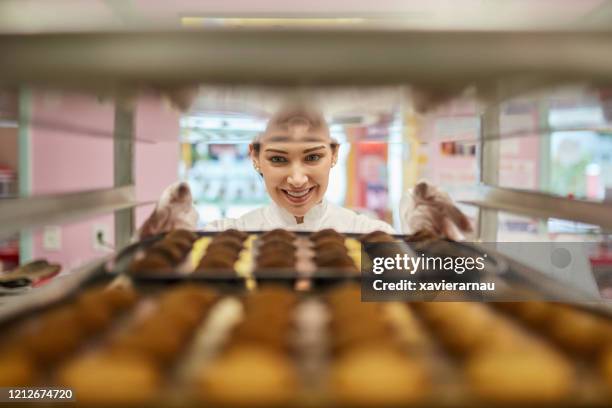 kvinna baker placera bakning tenn på cooling rack i köket - kyltråg bildbanksfoton och bilder