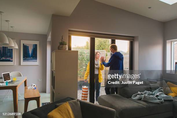 woman delivering items to her husband who is in self isolation at home - quarantäne stock-fotos und bilder