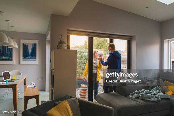 woman delivering items to her husband who is in self isolation at home - pandemic loneliness stock pictures, royalty-free photos & images