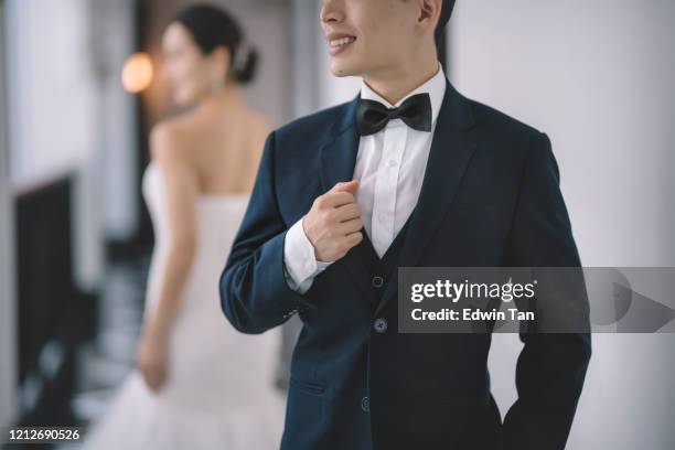 una coppia di nozze asiatica cinese in piedi al corridoio con completo completo e abito da sposa sorridente concentrandosi sullo sposo - chinese wedding dress foto e immagini stock