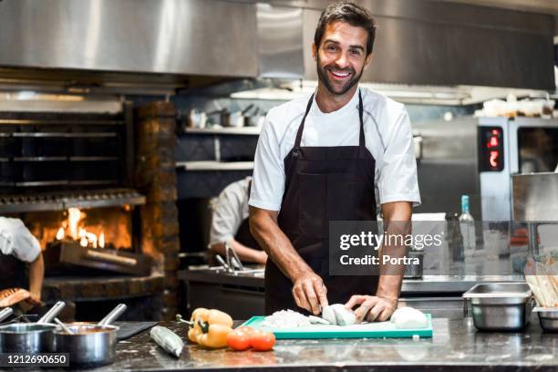 chef masculin confiant préparant la nourriture dans le restaurant - tablier photos et images de collection