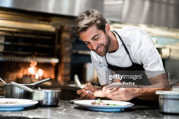 male cook garnishing food in commercial kitchen - restaurant chef stock pictures, royalty-free photos & images