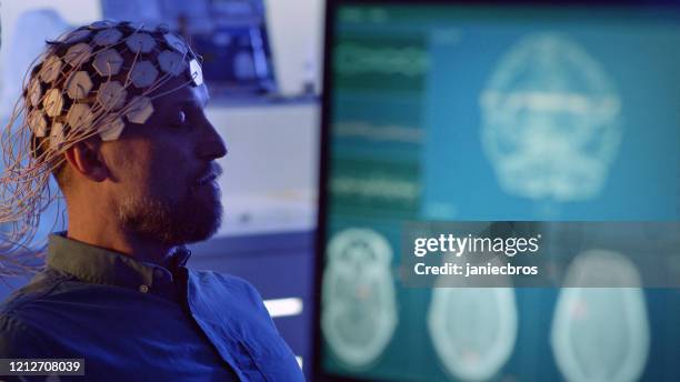 hombre usando auriculares de escaneo de ondas cerebrales. - medical scanner fotografías e imágenes de stock