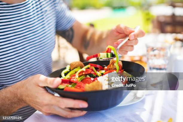 uomini che mangiano insalata greca - pranzo foto e immagini stock