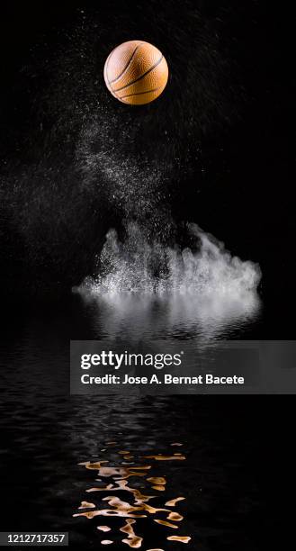 impact and rebound of a ball of basketball on a surface of land and powder reflected in the water. - ballon rebond stock-fotos und bilder