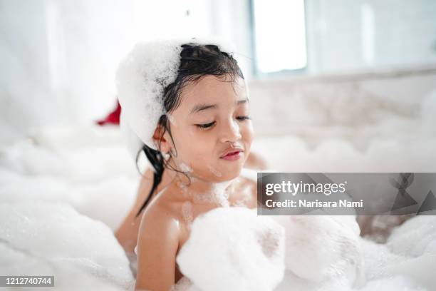 happy asian kid bathing concept. adorable girl in bathtub with fluffy soap bubble. - kids taking a shower stockfoto's en -beelden