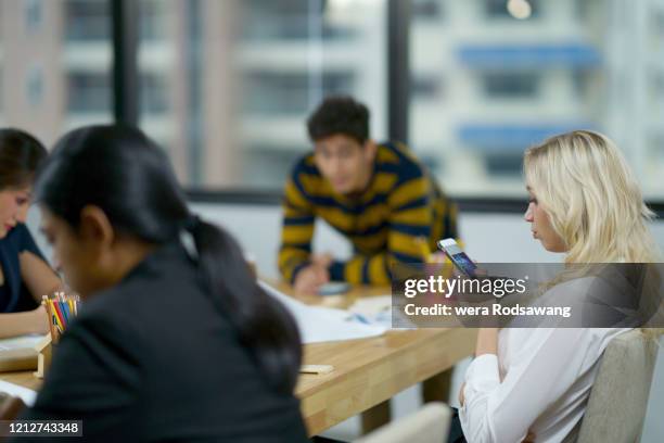 employees using cell phones at workplace - unbequemlichkeit stock-fotos und bilder