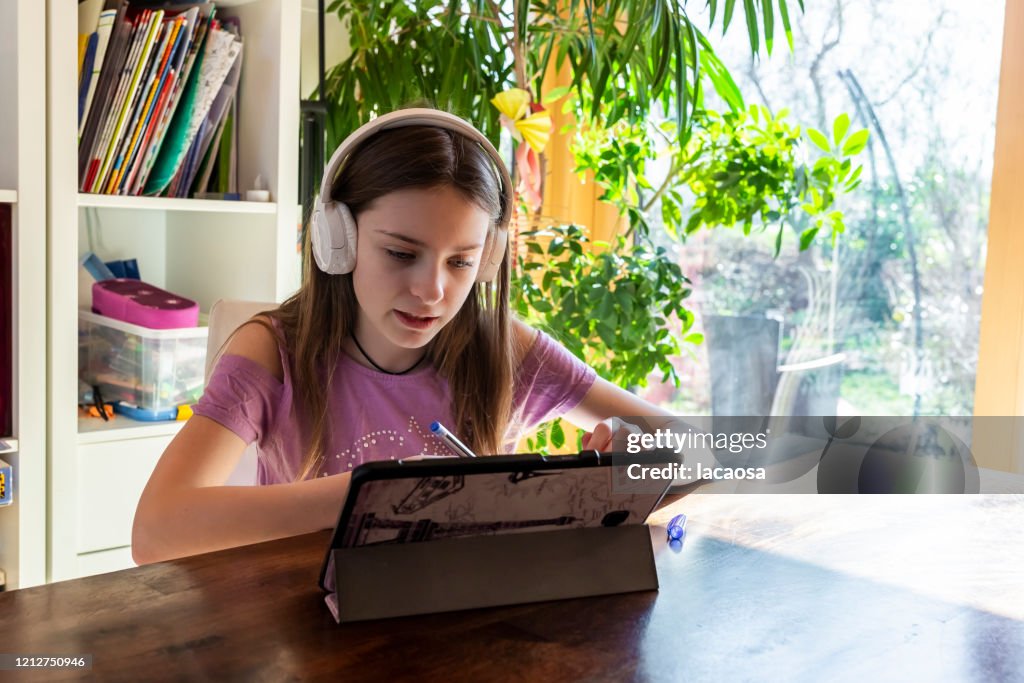 Girl doing homework with headphones and digital tablet