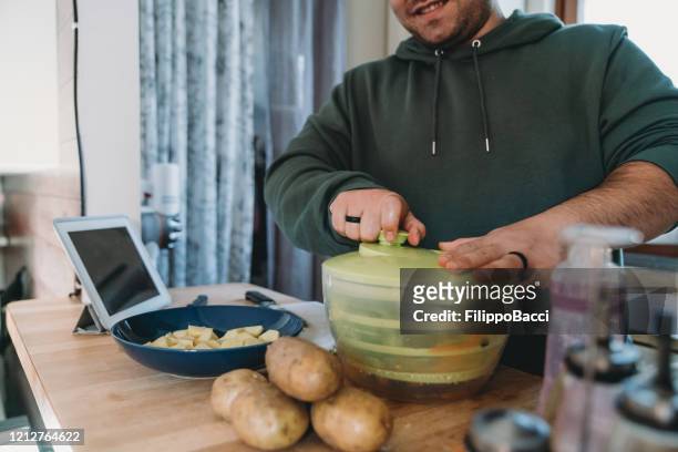 joven adulto preparando una ensalada fresca para el almuerzo - centrifugal force fotografías e imágenes de stock