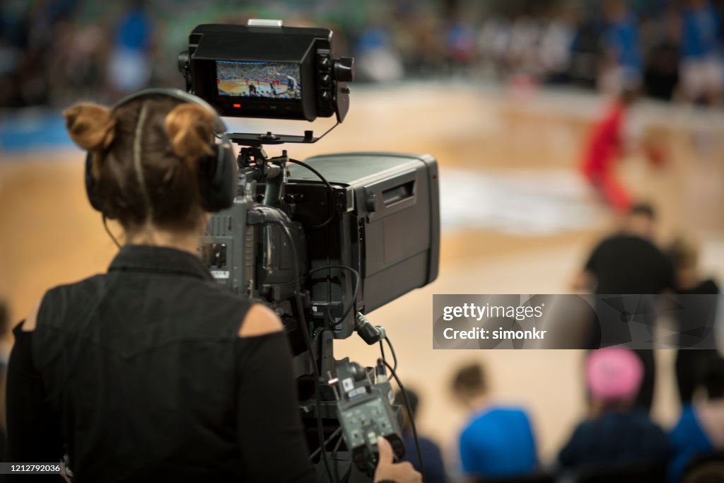 Mujer camarógrafo disparando juego de baloncesto