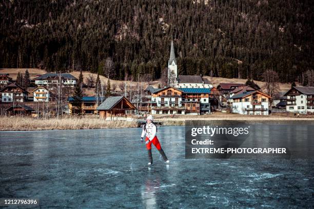 en amatör idrottskvinna som åker över en frusen sjö med bybakgrund - ice skate bildbanksfoton och bilder