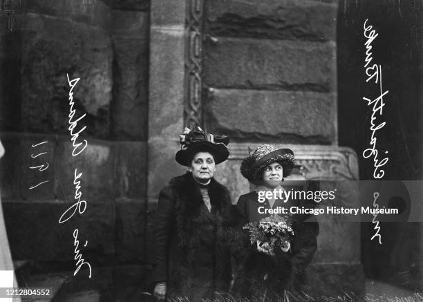 Delegates to the Women's Suffrage Legislature Jane Addams of Hull House and Miss Elizabeth Burke of the University of Chicago, standing outside a...