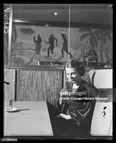 Woman drinking during the repeal of prohibition at the Palmer House Bar, featuring a Balinese scene mural painted by Honore Palmer Jr., inside the...