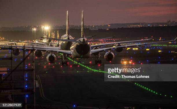 Lufthansa passenger airplanes are lined up at night at Frankfurt Airport, operated by Fraport AG as airlines are affected by travel bans related to...