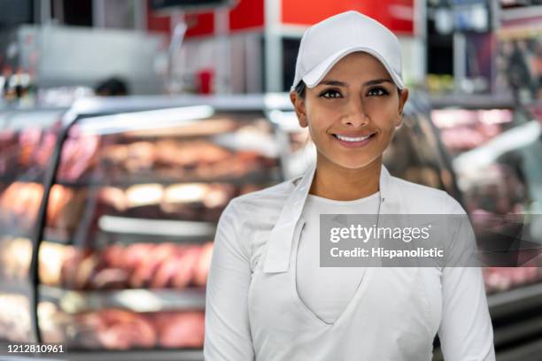 retrato de mulher bonita trabalhando em um açougue vestindo uniforme e sorrindo para a câmera - açougue - fotografias e filmes do acervo