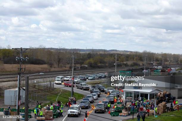 Cars line up as volunteers participate in a drive-through food bank at the New York State Fairgrounds on May 12, 2020 in Syracuse, New York. New York...