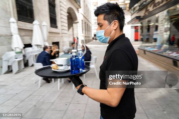 Waiter with his mask takes a service to a terrace in Santander, Spain, on May 12 which with the arrival of phase 1 of de-escalation, can already open...