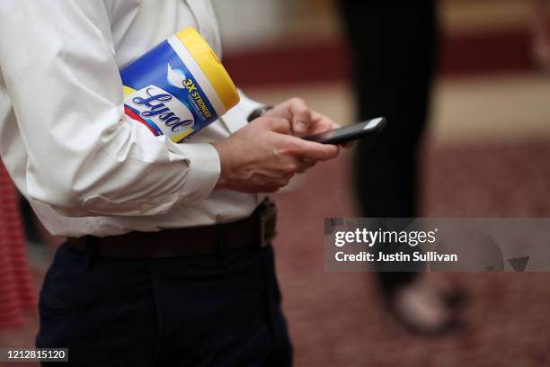An attendee holds a container of Lysol disinfecting wipes as San Francisco Mayor London Breed speaks during a press conference at San Francisco City...