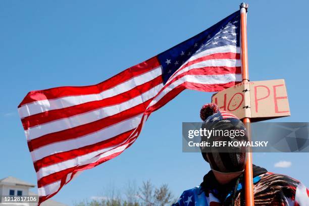 DemonstraA man holds a US flag outside the shop of Barber Karl Manke, who faces two misdemeanor charges for reopening his business despite state...