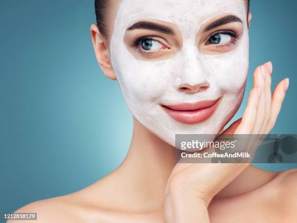 happy young girl with facial mask on her face - clay mask stock pictures, royalty-free photos & images
