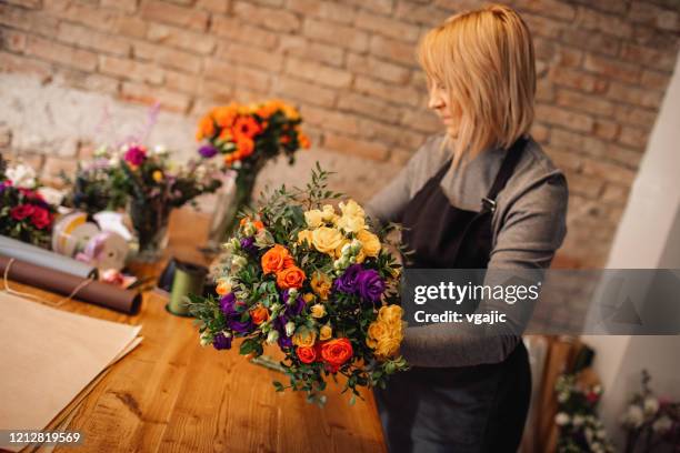 female florist arranging bouquet in flower shop - florist arranging stock pictures, royalty-free photos & images