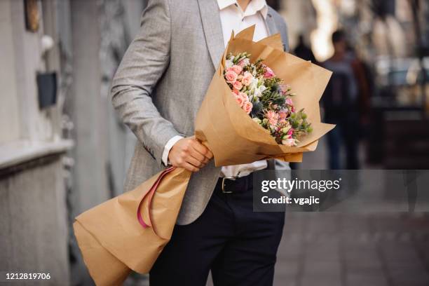 young man holding beautiful bouquet of fresh flowers - white flower paper stock pictures, royalty-free photos & images