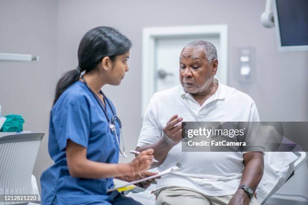 elderly male patient talking with female doctor stock photo - medical research stock pictures, royalty-free photos & images