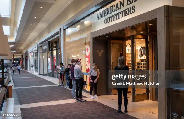 Shoppers wait in line for their turn to shop at a clothing store at a mall as a part of the effort to maintain social distancing on May 12, 2020 in...