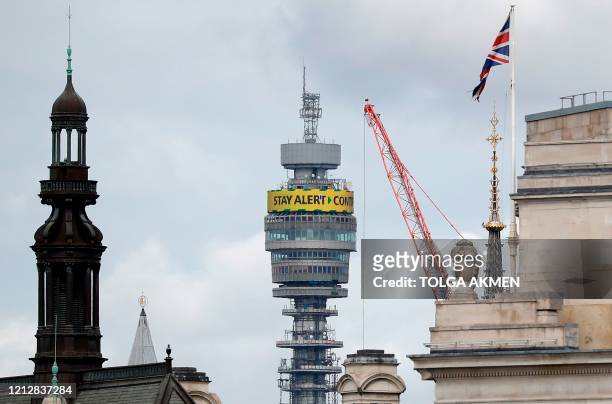 The British Government's new COVID-19 slogan "Stay Alert, Control the Virus, Save Lives" is pictured on the BT tower, in central London on May 13 as...