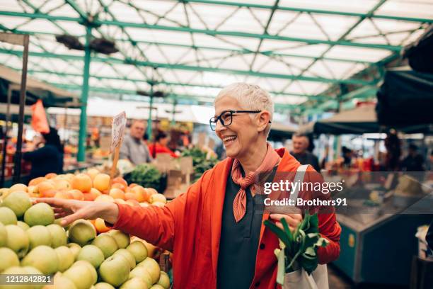 senior woman shopping at the farmer's market - market stall stock pictures, royalty-free photos & images