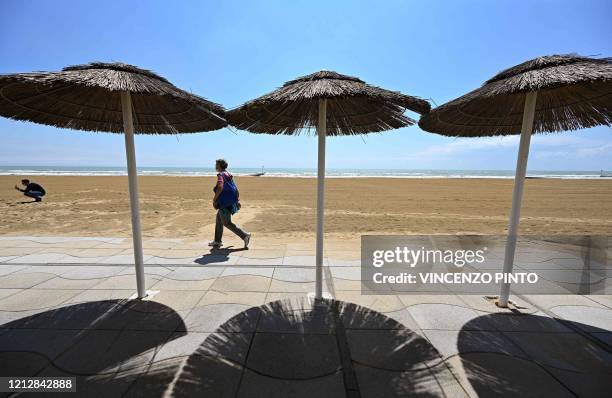 View taken on May 12, 2020 shows a person walking along a private beach and the seafront in Jesolo, near Venice, northeastern Italy, during the...