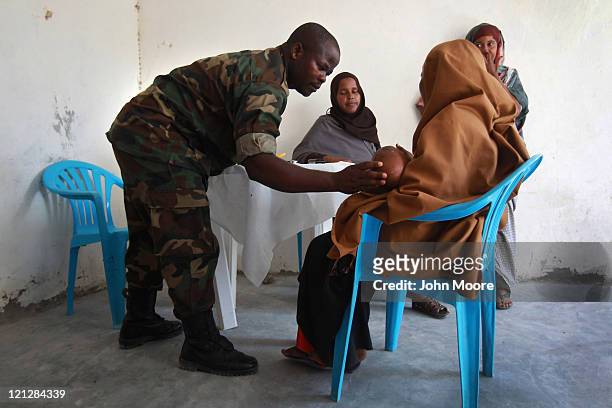Ugandan doctor checks a Somali child at an outpatient hospital run by the African Union Mission in Somalia , on August 17, 2011 in Mogadishu,...