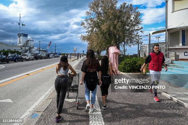 View taken on May 11, 2020 people go about along the seafront in Rimini on the Adriatic coast, northeastern Italy, during the country's lockdown...