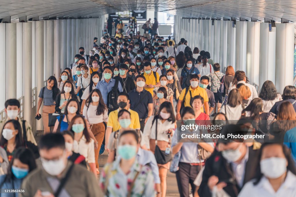 Crowds of Asian people wearing face protection while going to their workplace in Bangkok at morning rush hour