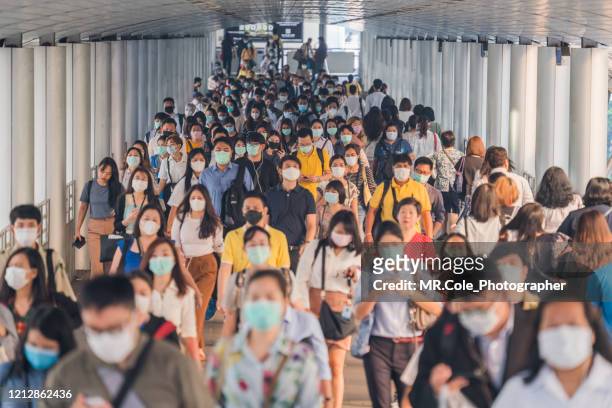 crowds of asian people wearing face protection while going to their workplace in bangkok at morning rush hour - malattia infettiva foto e immagini stock