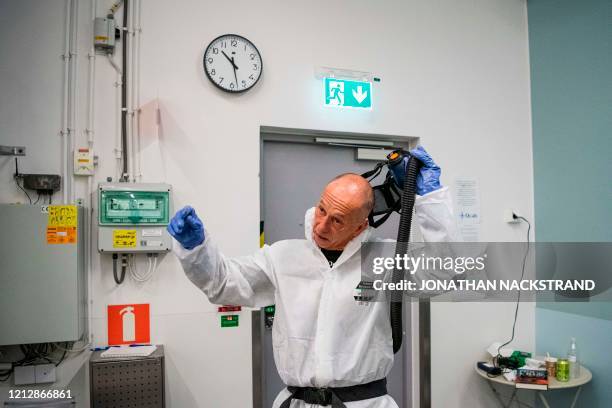 Healthcare worker takes off his protective gear after cleaning and disinfecting an ambulance at the Intensive Care Unit at Danderyd Hospital near...