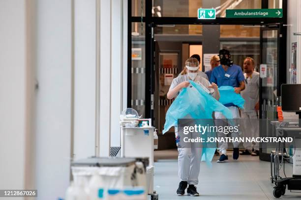 Healthcare workers put on protective gear as they prepare to receive a patient at the Intensive Care Unit at Danderyd Hospital near Stockholm on May...