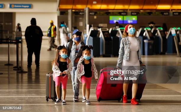 Yadira Barajas walks with her children Owen Vargas and 6-year-old twins Madison and Madelyn Contreras, as they prepare for a flight to Mexico at Tom...