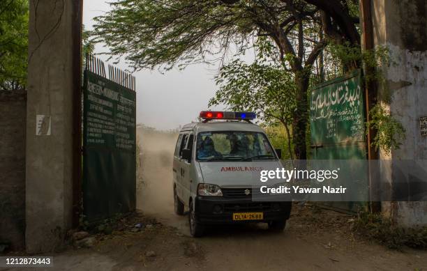 An ambulance comes out of the graveyard after handing over the body of a 42 years old woman who died from the coronavirus disease , to her relatives,...