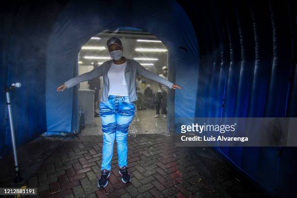 Woman walks through a disinfection tunnel at Dr. Armando Gomes de Sá Couto ER during the coronavirus pandemic on May 13, 2020 in São Gonçalo, Brazil....